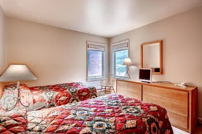 a bedroom with two beds and a desk and a mirror at Forest Condominiums by Vail Resorts in Keystone