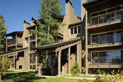 an apartment building with balconies and a tree at Forest Condominiums by Vail Resorts in Keystone
