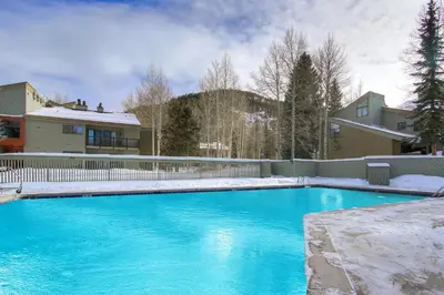 a swimming pool with blue water in front of a house at Forest Condominiums by Vail Resorts in Keystone