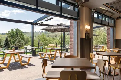 a restaurant with tables and chairs and large windows at The Eddy Taproom & Hotel in Golden