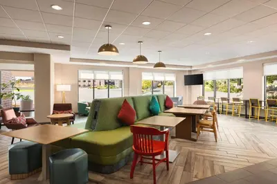 a lobby with a green couch and tables and chairs at Home2 Suites by Hilton Denver West / Federal Center in Lakewood