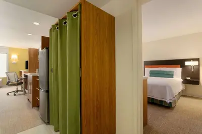 a hotel room with a bed and a bedroom with green dividers at Home2 Suites by Hilton Denver West / Federal Center in Lakewood
