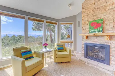 a living room with two chairs and a fireplace at Mountain Views and Hot Tub Airy Forest Escape! in Black Hawk