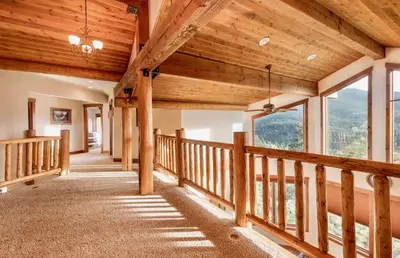 a hallway in a log home with wooden ceilings and windows at Elk Summit Vacation Home at Windcliff home in Estes Park