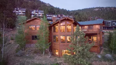 a large wooden house in the middle of a forest at Elk Summit Vacation Home at Windcliff home in Estes Park