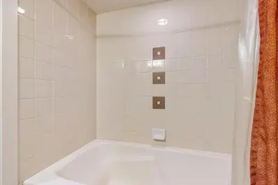 a white bath tub in a white tiled bathroom at Ski-In Ski-Out Modern Mountain Condo in Winter Park