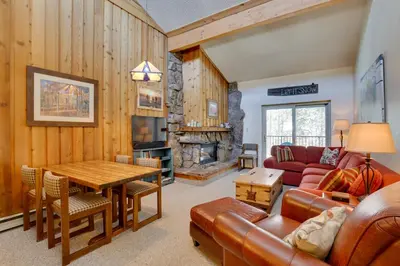a living room with a couch and a table and a fireplace at Colorado Ski Condo in the Heart of Winter Park in Winter Park
