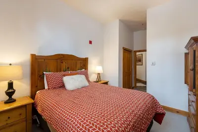 a bedroom with a bed with a red comforter at 3059 The Timbers condo in Keystone