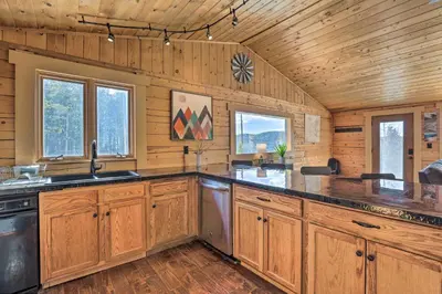 a large kitchen with wooden walls and wooden cabinets at 2 Mi to St Marys Glacier Modern Cabin with Hot Tub in Idaho Springs