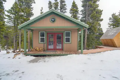 a tiny house with a red door in the snow at 2 Mi to St Marys Glacier Modern Cabin with Hot Tub in Idaho Springs