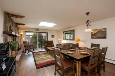 a dining room and living room with a table and chairs at Hi Country Haus Unit 2115 by Stay WinterPark in Winter Park