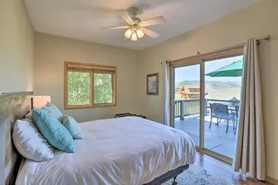 a bedroom with a bed and a balcony with an umbrella at Ski and Bike Home with Deck and Hot Tub in Granby! in Granby