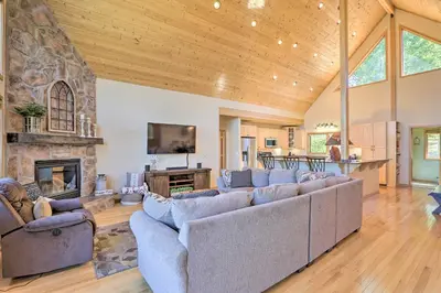 a large living room with couches and a stone fireplace at Ski and Bike Home with Deck and Hot Tub in Granby! in Granby