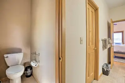a bathroom with a white toilet and a door at Ski and Bike Home with Deck and Hot Tub in Granby! in Granby