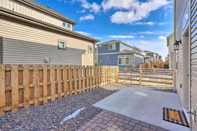 a wooden fence next to a house with a driveway at Modern Aurora Getaway 22 Mi to Downtown Denver in Watkins