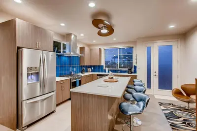 a kitchen with a stainless steel refrigerator and blue cabinets at Elegant Townhome near Old Town, Breweries and River! in Fort Collins
