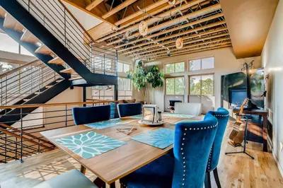 a dining room with a wooden table and blue chairs at Old Town Loft Oasis with Amazing Rooftop Deck! in Fort Collins