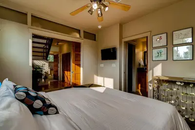 a bedroom with a white bed with a ceiling fan at Old Town Loft Oasis with Amazing Rooftop Deck! in Fort Collins