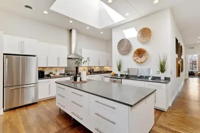 a large kitchen with white cabinets and stainless steel appliances at The Penthouse Loft in the Heart of Old Town! in Fort Collins