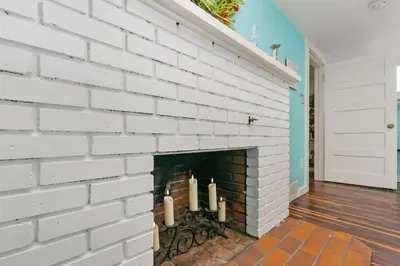 a white brick fireplace with three candles on it at Mulberry Place - A Charming Cottage Near Old Town! in Fort Collins