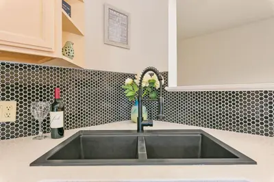 a sink in a kitchen with a bottle of wine at Mulberry Place - A Charming Cottage Near Old Town! in Fort Collins