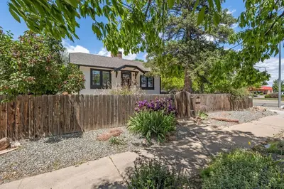 a home with a wooden fence and flowers at Mulberry Place - A Charming Cottage Near Old Town! in Fort Collins