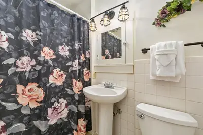 a bathroom with a flower shower curtain and a sink at Mulberry Place - A Charming Cottage Near Old Town! in Fort Collins