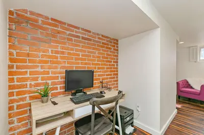 a desk with a computer on a brick wall at Mulberry Place - A Charming Cottage Near Old Town! in Fort Collins