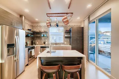 a kitchen with a large island with bar stools at Fancy Townhome near Old Town, Breweries and River! in Fort Collins