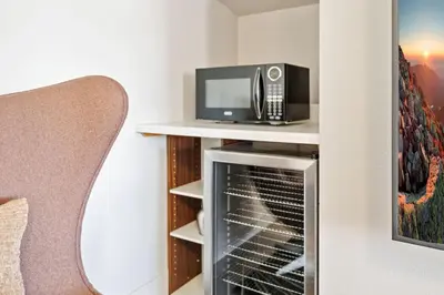 a microwave sitting on a shelf next to a chair at Fancy Townhome near Old Town, Breweries and River! in Fort Collins