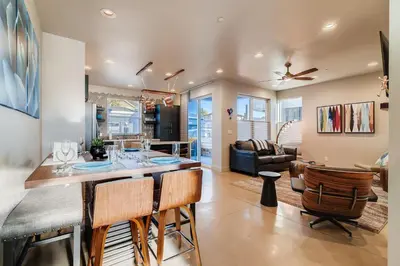 a kitchen and living room with a bar with chairs at Fancy Townhome near Old Town, Breweries and River! in Fort Collins