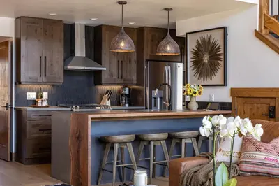 a kitchen with wooden cabinets and a island with bar stools at Chic Lakefront Cabin - Unbeatable Views! Jacuzzi, Two Patios, Indoor/Outdoor Fireplace in Estes Park