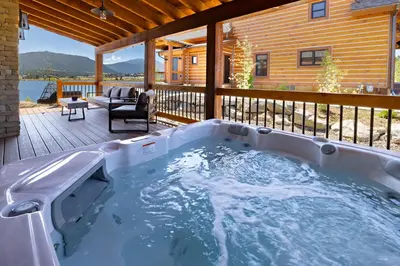 a hot tub on the deck of a house at Chic Lakefront Cabin - Unbeatable Views! Jacuzzi, Two Patios, Indoor/Outdoor Fireplace in Estes Park
