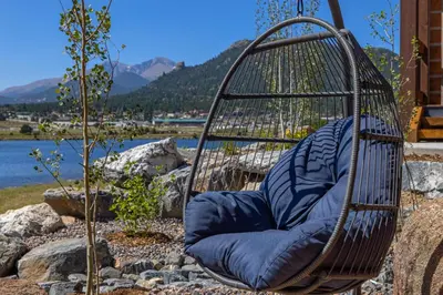 a swing with a blue pillow sitting on the ground at Chic Lakefront Cabin - Unbeatable Views! Jacuzzi, Two Patios, Indoor/Outdoor Fireplace in Estes Park