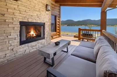 a living room with a fireplace on a deck at Chic Lakefront Cabin - Unbeatable Views! Jacuzzi, Two Patios, Indoor/Outdoor Fireplace in Estes Park