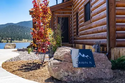 a sign on a rock in front of a cabin at Chic Lakefront Cabin - Unbeatable Views! Jacuzzi, Two Patios, Indoor/Outdoor Fireplace in Estes Park