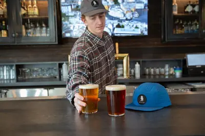 a man standing at a bar with two beers at Gravity Haus Winter Park in Winter Park