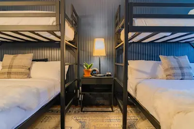 two bunk beds in a room with a desk and a lamp at Gravity Haus Winter Park in Winter Park