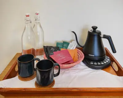two black coffee mugs on a wooden tray with bottles at Boulder Guest House in Boulder