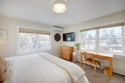 a bedroom with a bed and a desk and windows at Boulder Guest House in Boulder