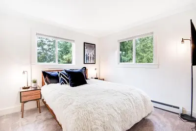 a white bedroom with a bed and two windows at Modern High Country Haus in Winter Park