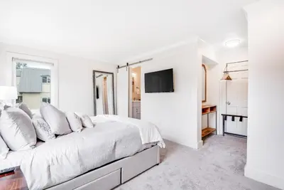 a white bedroom with a bed and a tv at Modern High Country Haus in Winter Park