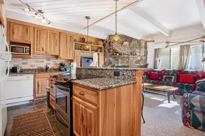 a kitchen with wooden cabinets and a living room at Lakeview A-303 - Dillon in Dillon