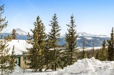 a house in the snow with trees and mountains at Snowscape 06 - Wildernest in Silverthorne