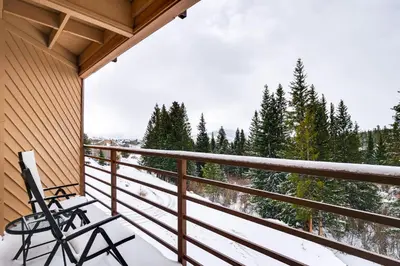 a chair on a balcony with a view of trees at 11 Mi to Keystone Resort Condo in Silverthorne in Silverthorne