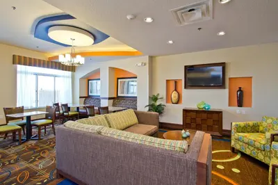 a living room with couches and a dining room at Holiday Inn Express and Suites Denver East Peoria Street by IHG in Denver