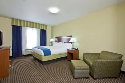 a hotel room with a bed and a chair at Holiday Inn Express and Suites Denver East Peoria Street by IHG in Denver