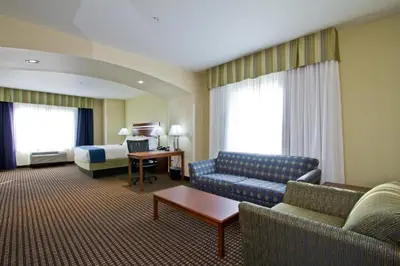 a hotel room with a couch and a bed at Holiday Inn Express and Suites Denver East Peoria Street by IHG in Denver