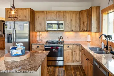 a kitchen with wooden cabinets and stainless steel appliances at Mountain Willow at Grand Park home in Fraser