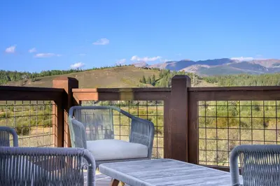 a patio with chairs and a table and a view of the mountains at Mountain Willow at Grand Park home in Fraser